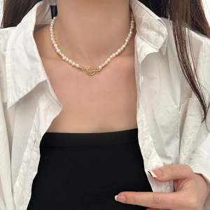 Detail view of a natural freshwater pearl necklace with a gold OT clasp on a model