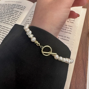 Close-up of Baroque pearl bracelet with golden OT toggle clasp worn by a female model