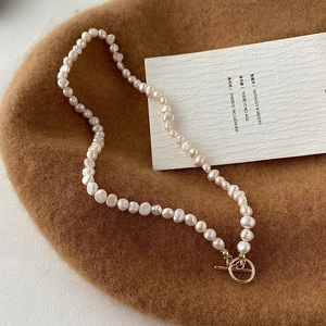 Macro detail of Baroque freshwater pearl necklace with a golden vintage toggle clasp