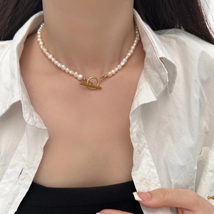 Gros plan d'un collier de perles d'eau douce avec un fermoir OT doré sur un mannequin