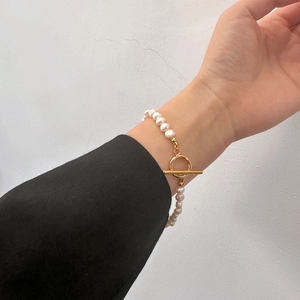 Détail d'un bracelet en perles d'eau douce avec fermoir OT doré sur le poignet
