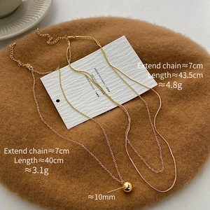 Detail of 18k gold plated ball necklaces with measurement data on textured background