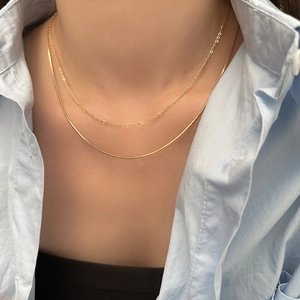 Detail of layered gold choker necklace featuring a snake chain and delicate ring link design