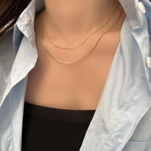 Detail of layered gold choker with snake and cable chain design on female model