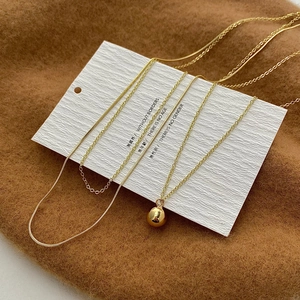 Minimalist gold ball necklace set featuring layered snake and link chains on white card