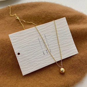 Detailed view of a minimalist golden ball pendant necklace with a polished metallic finish