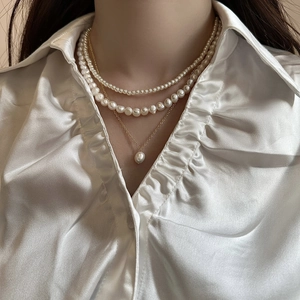 Gros plan sur le collier à trois rangs en perles d'eau douce avec pendentif doré