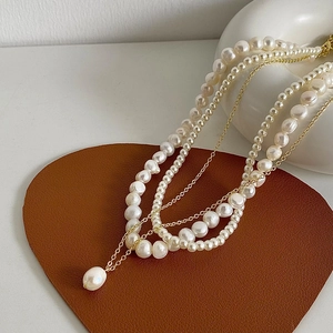 Détail d'un collier à trois rangs en perles d'eau douce et pendentif doré