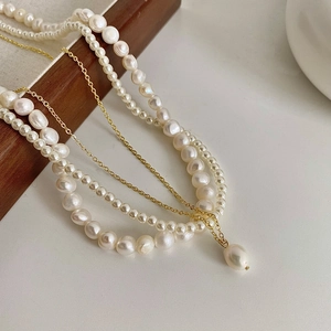 Détail du collier à trois rangs de perles d'eau douce avec un pendentif doré chic