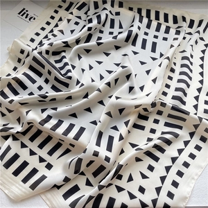 Detail of soft silk-like fabric featuring black geometric patterns on creamy white