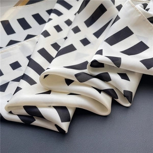 Macro view of geometric black and white silk scarf showing smooth texture and rolled edges