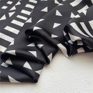 Detailed close-up of geometric black and white patterned silk scarf with premium texture