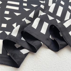 Close-up of geometric black and white silk scarf with premium stitched edge texture