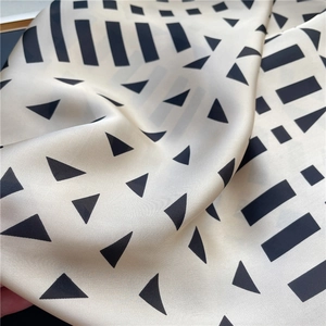 Detailed view of geometric patterned silk scarf with smooth texture and modern print