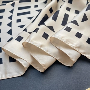 Detailed view of cream and black geometric silk scarf with elegant satin luster finish