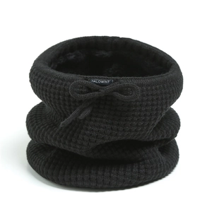 Detailed view of black waffle knit neck warmer with plush lining and bow decoration