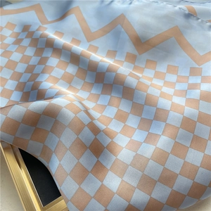 Gros plan d'un foulard en soie léger avec motif à carreaux bleu et beige et éclat soyeux