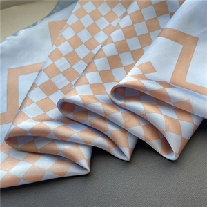 Gros plan détaillé d'un foulard en soie à damier bleu et orange sur cuir foncé