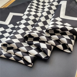 Gros plan sur la texture du foulard en soie à carreaux noirs et blancs sur cuir