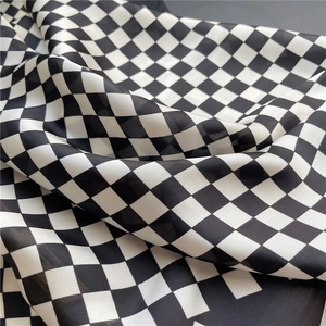 Détail d'un foulard en soie à damier montrant la texture douce et le drapé du mousseline