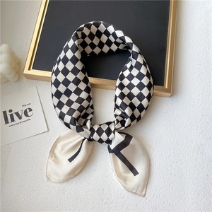 Détail d'un foulard en soie à damier noir et blanc avec une texture lisse et brillante