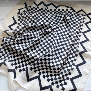 Détail d'un foulard en soie à damier montrant le tissu crème et les bords ondulés