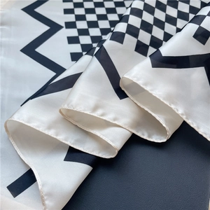 Vue détaillée du foulard en satin de soie montrant le motif géométrique noir et blanc