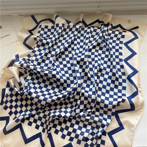 Détail d'un foulard carré effet soie avec motif damier bleu marine et texture lisse