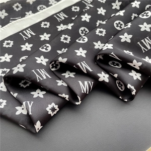Detail of silk-like scarf with black and white monogram print and elegant fabric drape