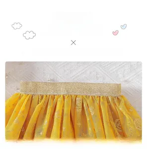 Detail of yellow tulle tutu skirt showing golden sequin elastic waistband and lace layers