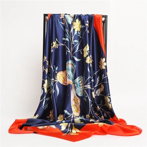 Detailed drape of navy floral silk scarf with butterfly pattern and orange border