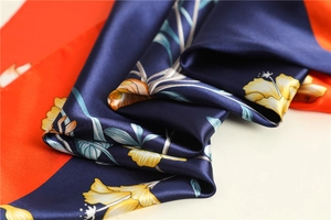 Close-up of luxury navy and orange floral silk scarf texture with detailed prints