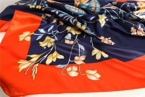 Close-up of silk scarf showing vibrant butterfly and floral prints with satin texture