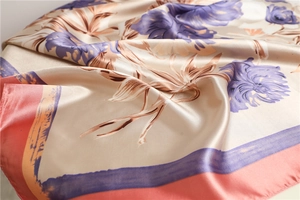 Detail of elegant floral satin scarf with champagne base and coral pink border edges