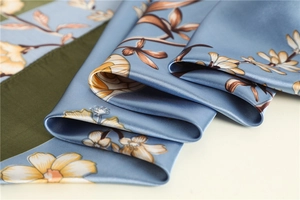 Detail of silk satin scarf showing blue and green patchwork with floral patterns