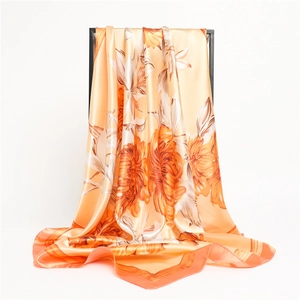 Close-up of elegant floral silk scarf with orange flower prints on a black display rack