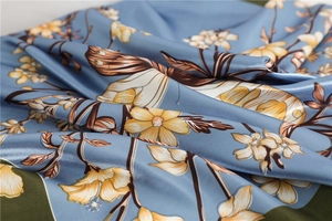 Detailed close-up of blue silk scarf with yellow floral and butterfly patterns