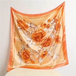 Detailed view of large floral satin silk square scarf with orange and cream patterns