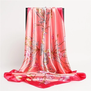 Detail of coral pink silk scarf with floral butterfly print showing the elegant drape