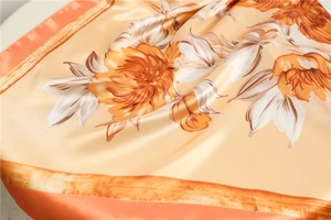 Detail of elegant orange floral print satin silk scarf with soft drape and glossy finish