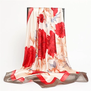 Detailed close-up of an elegant satin silk scarf with red peony floral prints and gray borders