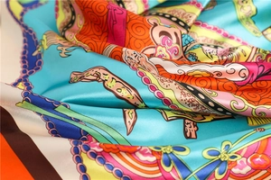 Detailed close-up of glossy satin silk scarf showing intricate floral and chain patterns
