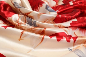 Macro detail of glossy satin fabric with red floral prints and soft elegant drapes