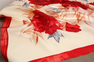 Close-up of elegant floral silk scarf showing red peony print and glossy satin texture