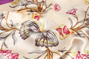 Close-up of champagne silk scarf featuring elegant butterfly and floral patterns with glossy finish