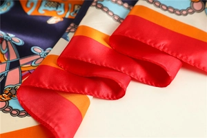 Detail of silk-like satin scarf featuring intricate chain patterns and rolled edges