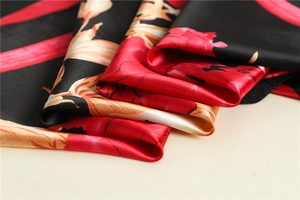 Close-up of elegant black satin scarf with vibrant red and orange floral prints