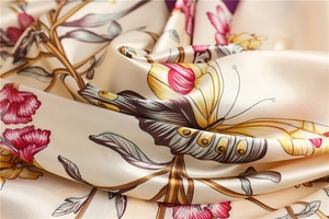 Macro view of silky floral butterfly pattern scarf showing smooth satin fabric texture