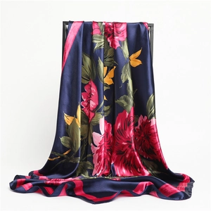 Close-up of silky satin scarf with floral prints in pink and yellow on navy blue base
