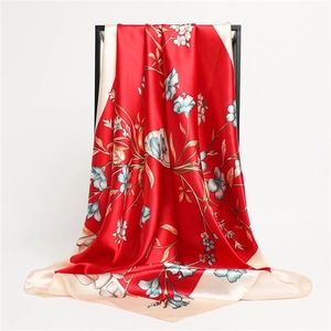 Detail of red floral silk scarf draped on a black rack showing smooth texture and pattern